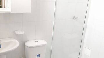 A bathroom with a toilet, sink, and glass shower enclosure.