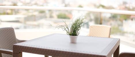 Un balcón con mesa y sillas, una planta en maceta y vistas a la ciudad.