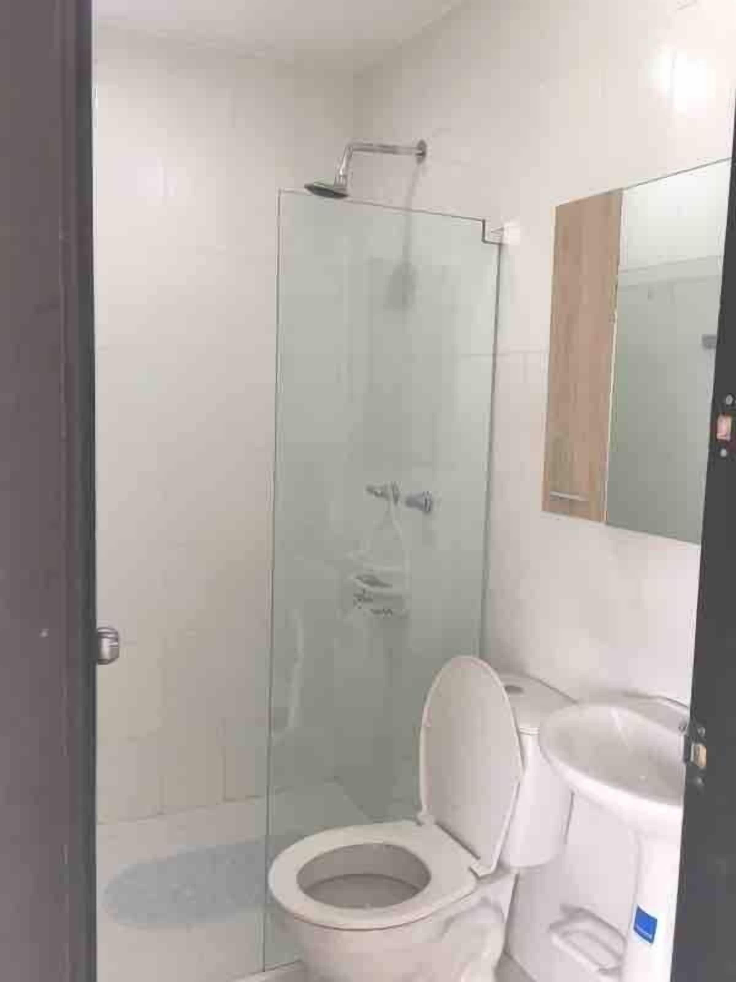 A bathroom with a glass shower enclosure, a toilet, and a sink.