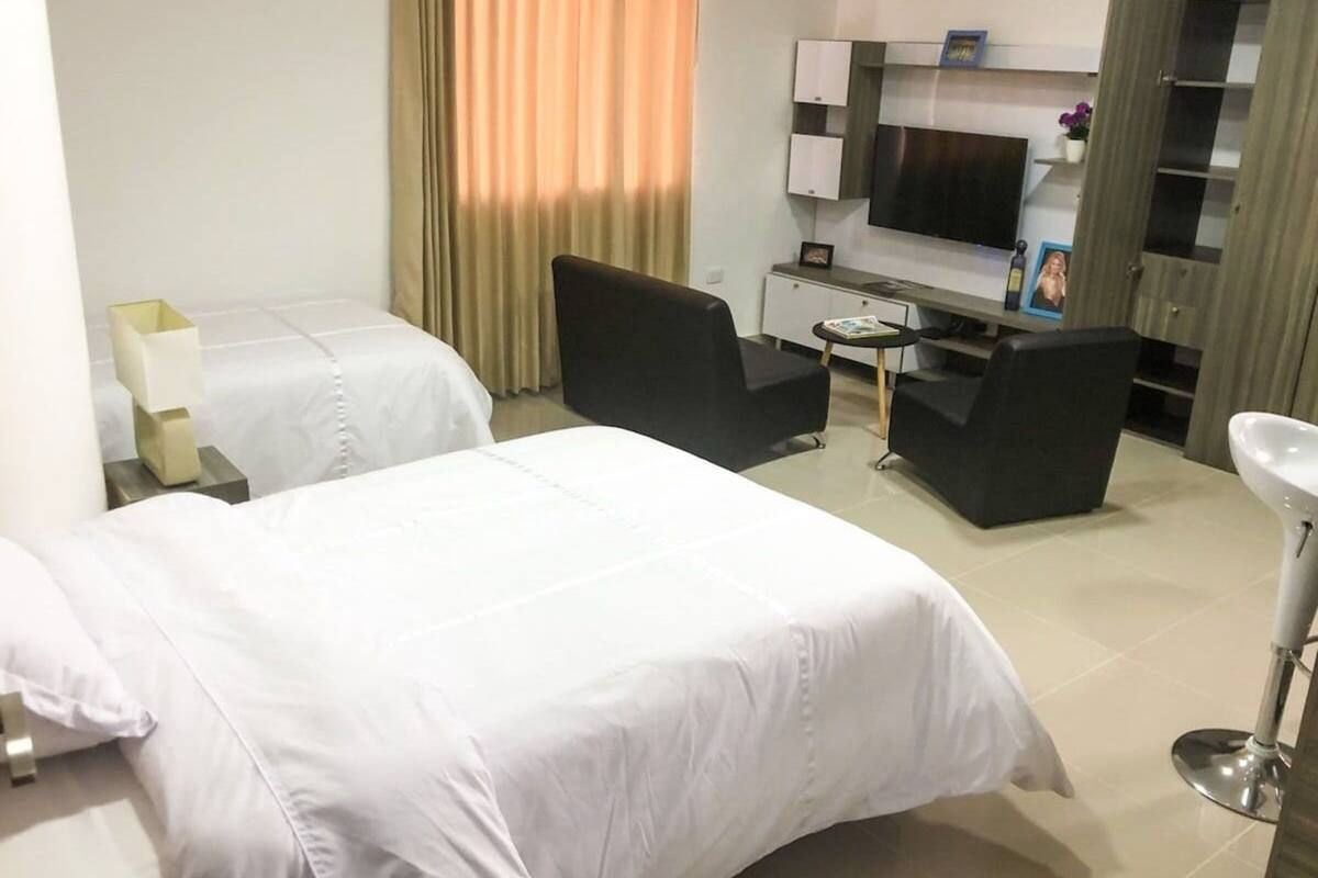 A hotel room with two beds, a TV, a desk, and a small table.