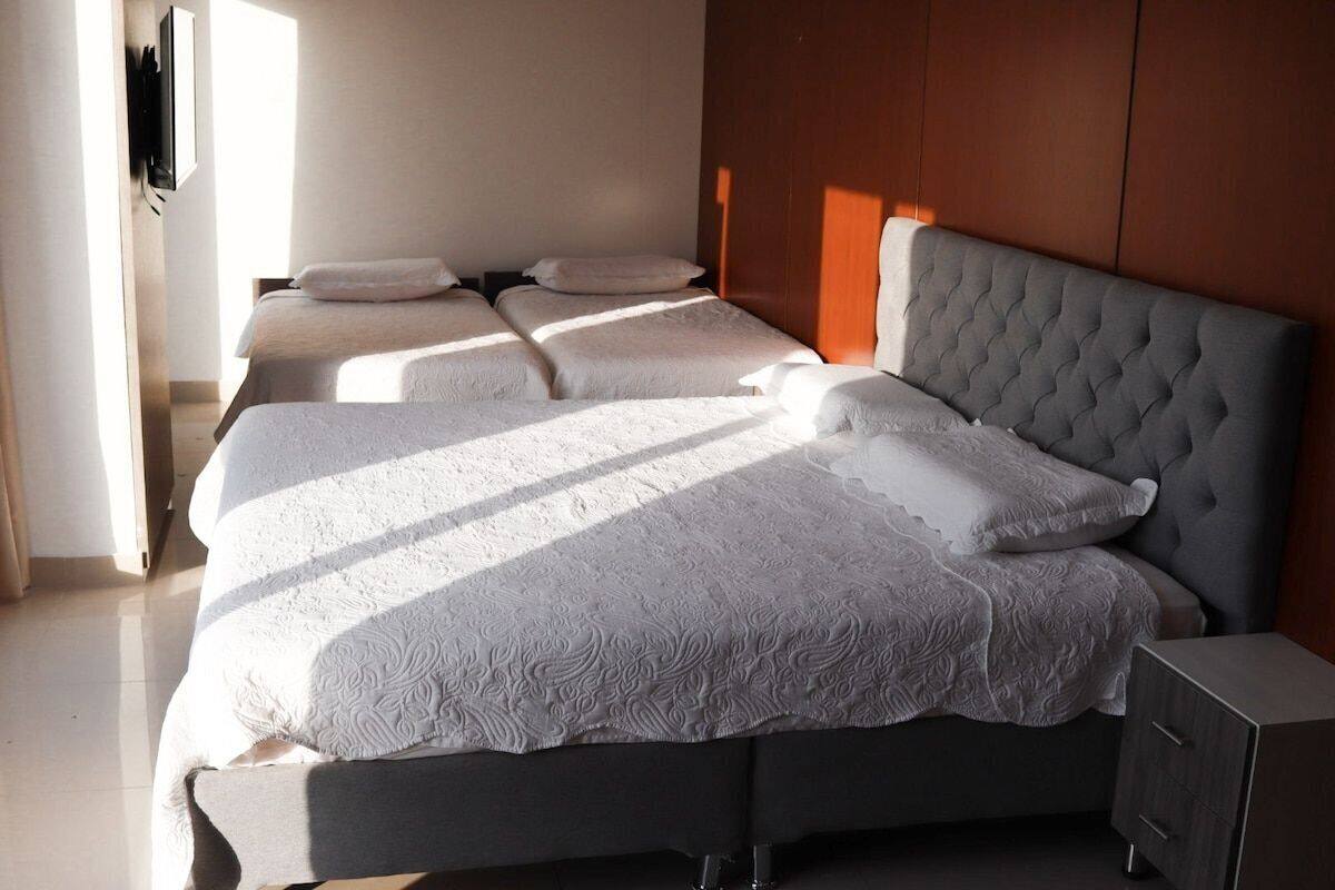A hotel room with a large bed, a bedside table, and a wooden headboard.