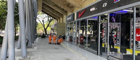 Un escaparate con fachada de vidrio, un logotipo rojo y una variedad de zapatos exhibidos.