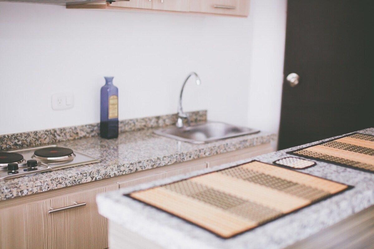 A kitchen with granite countertops, a gas stove, a sink, and a blue bottle.
