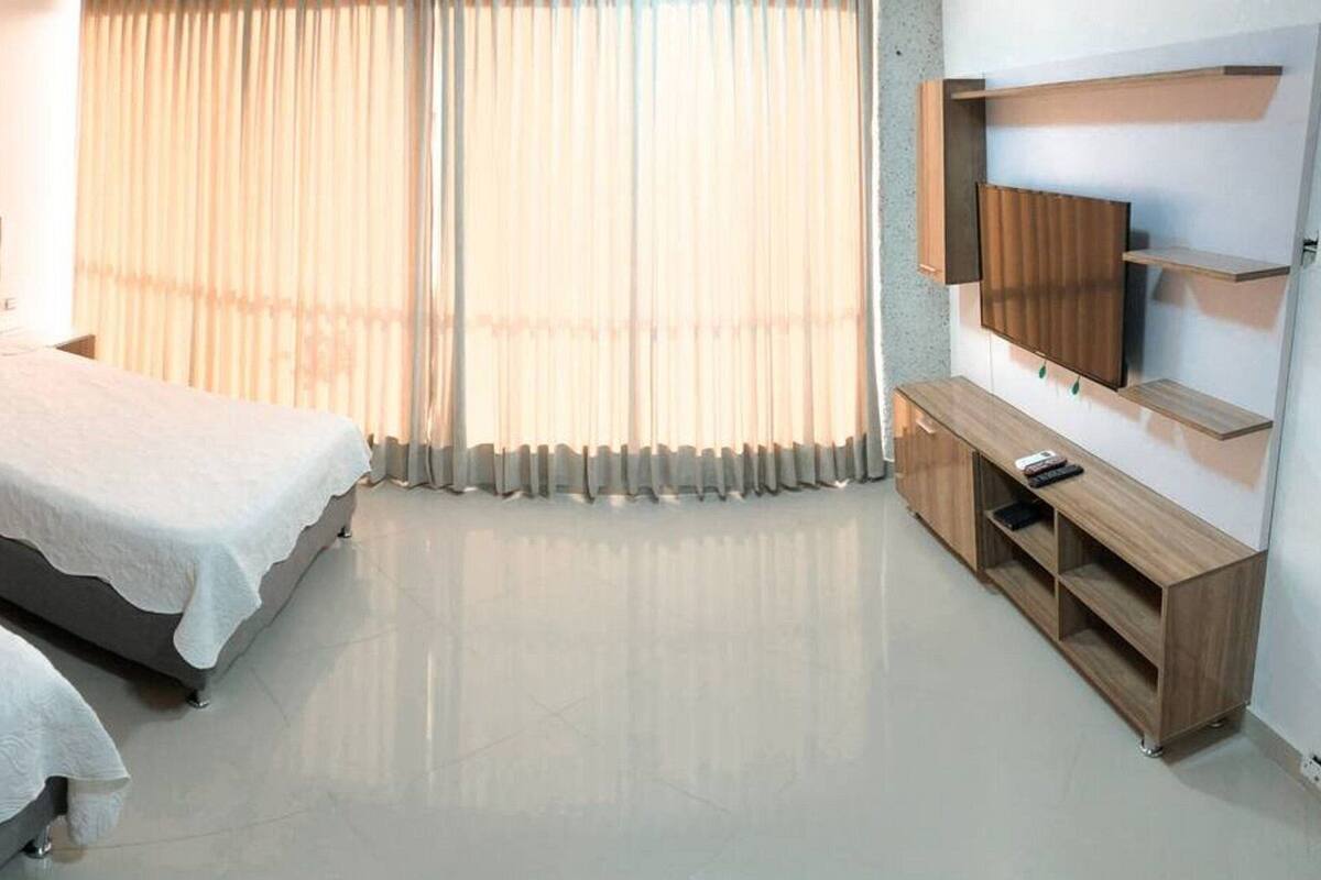 A hotel room with two beds, a TV, and a wooden cabinet.