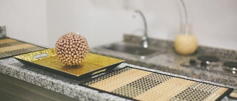 A kitchen counter with a decorative golden sphere on a black tray, a sink, and a yellow fruit bowl in the background.