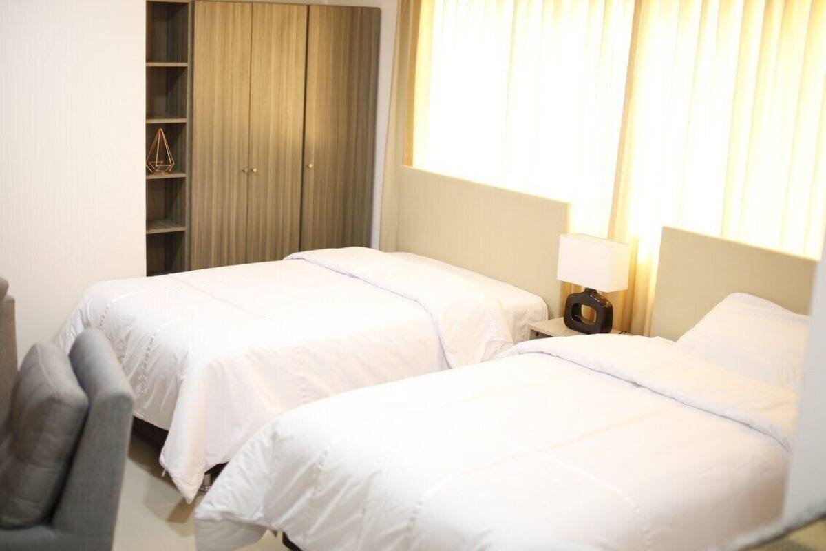 A hotel room with two beds, a wardrobe, a desk, and a chair.