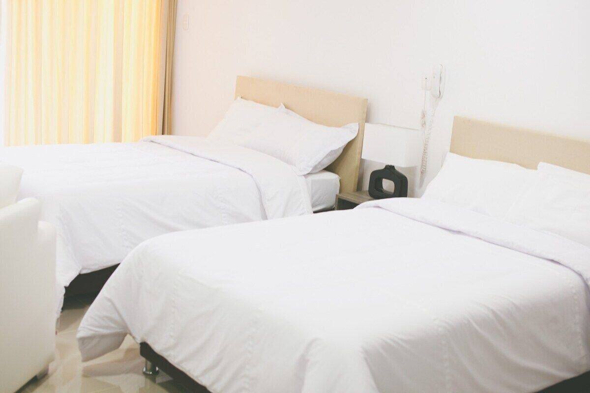 A hotel room with two single beds, a bedside table with a lamp, and a telephone.