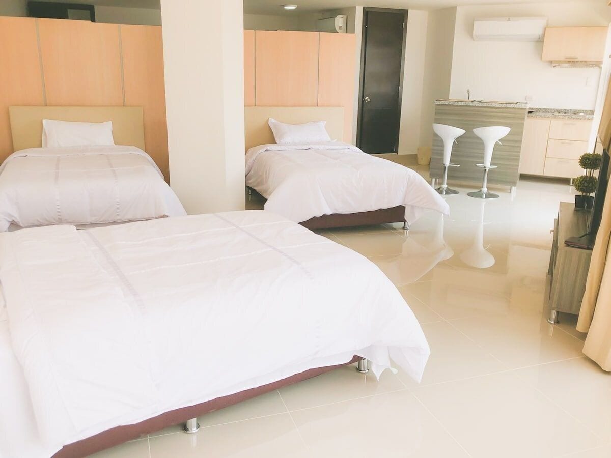 Une chambre d’hôtel avec deux lits, une kitchenette et une salle de bain.