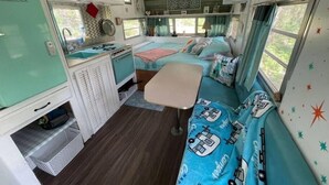 Interior compacto de una caravana con kitchenette, una cama y una zona de estar.