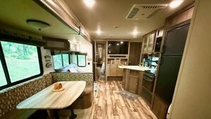 A compact kitchen with a dining area, a refrigerator, and a window with a view.