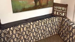 A painting of a bison on a wall, a cushion with 'Campfire Tonight at Dusk' text, and a patterned wall.