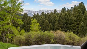 A hot tub in a forested area with a mountain view in the background. - Cabin near Bridger Bowl with Hot Tub!  (Bozeman)