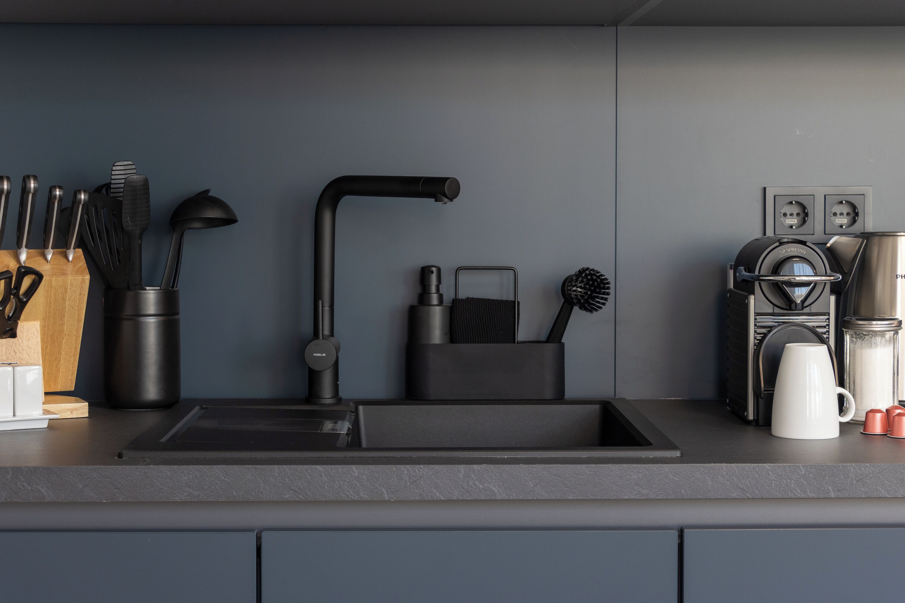Eine moderne Küche mit einem schwarzen Spülbecken, Edelstahlgeräten und einer Kaffeemaschine.