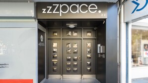 A storefront with a dark facade and a large entrance door. - zzzpace Smart-Hotel Bielefeld (Bielefeld)