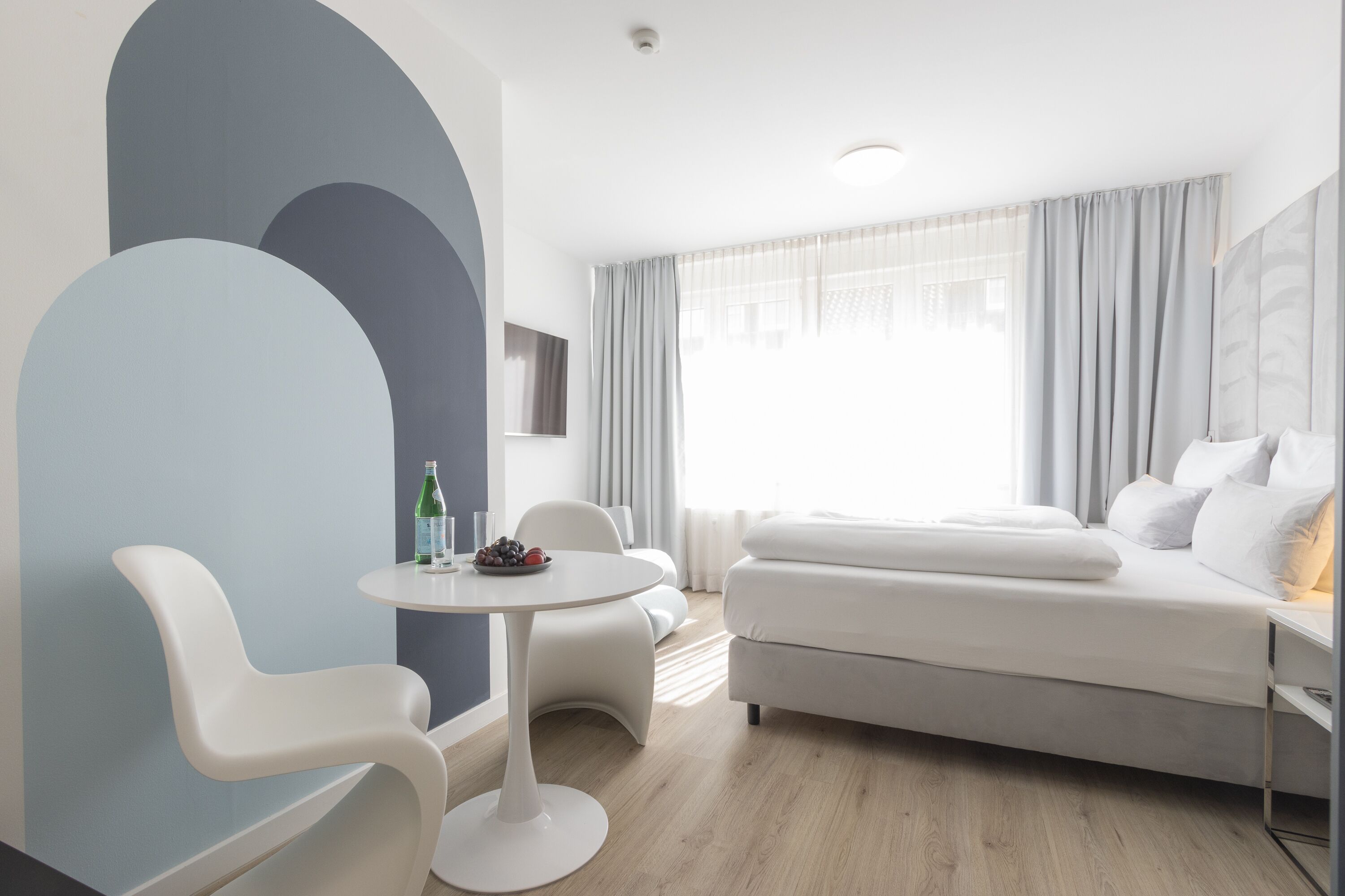 A modern hotel room with a bed, a round table, and a chair.