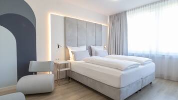 Un dormitorio moderno con una cama grande, mesitas de noche y una silla.