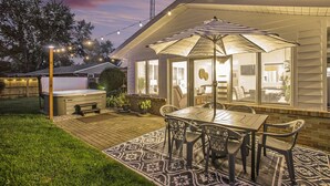 Eine Terrasse mit Tisch, Stühlen, einem Whirlpool und Lichterketten.