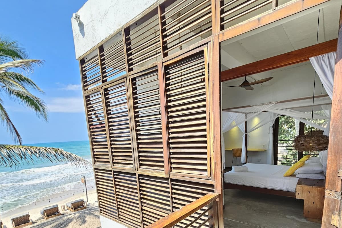 A wooden deck with a bed and a view of the beach.