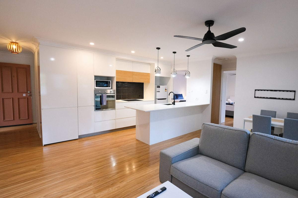 A modern kitchen with white cabinets, a built-in microwave, and a central island with a sink.