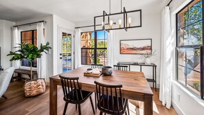 A dining area with a wooden table, black chairs, and a hanging light fixture.