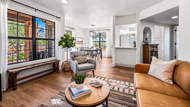 A spacious living room with a wooden bench, a leather sofa, and a dining area in the background.