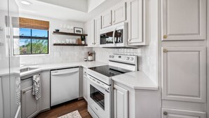 A modern kitchen with white cabinetry, a built-in oven, and a microwave.