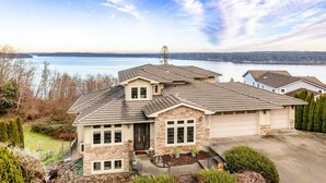Ein zweistöckiges Haus mit Naturstein-Fassade, einer Garage und Blick auf einen See.