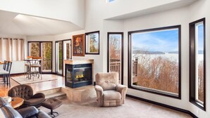Ein geräumiges Wohnzimmer mit Kamin, großen Fenstern und Seeblick.