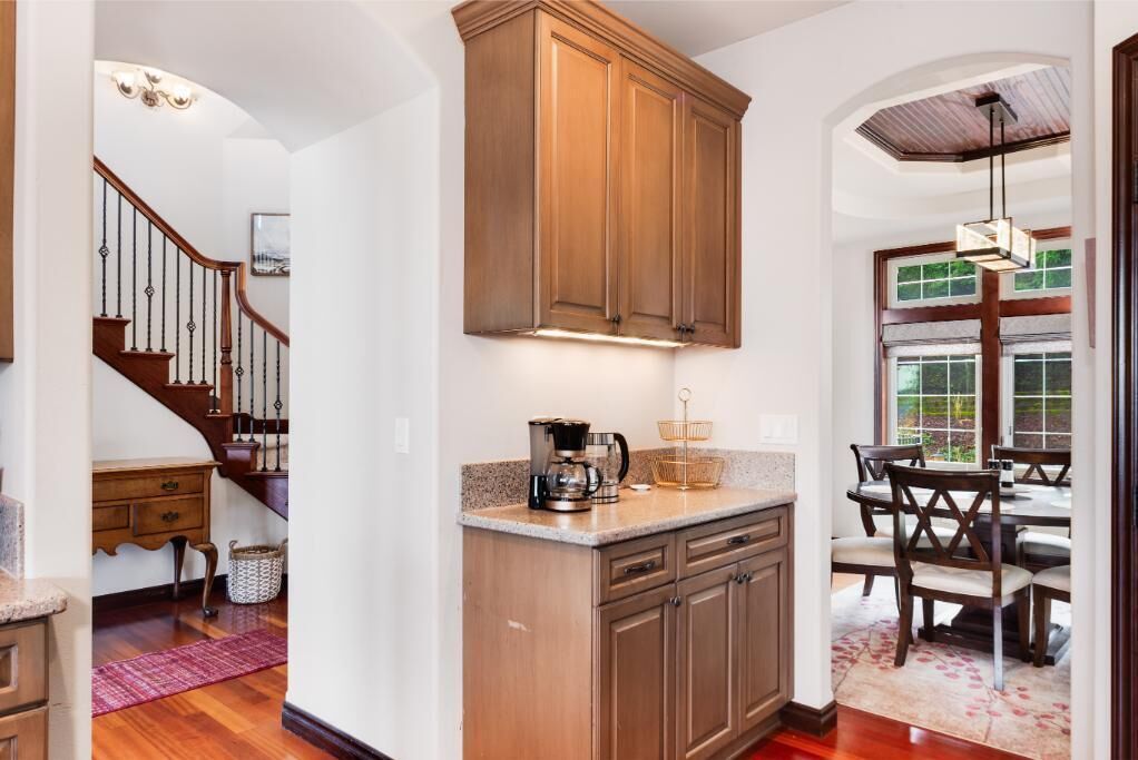 A kitchen with wooden cabinets, a coffee maker, and a dining area with chairs and a table.