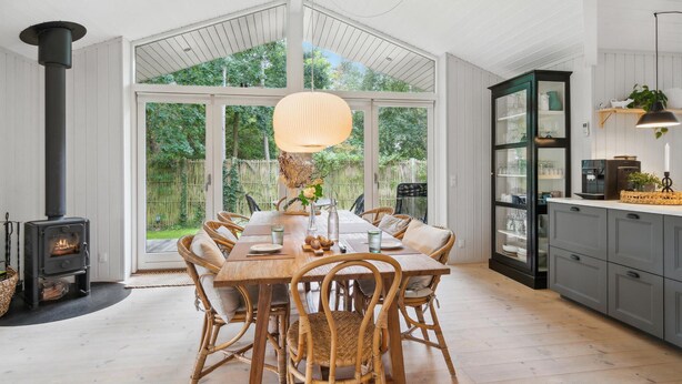 Een ruime keuken met een grote eettafel, rieten stoelen en een inbouwfornuis.