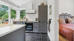 Een kleine keuken met een inbouwoven, een zithoek met een bank en een bed met een beddengoed met een patroon.