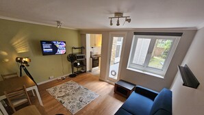 A living room with a sofa, a TV, a fan, a small table, and a chair. - Peaceful & Elegant (London)