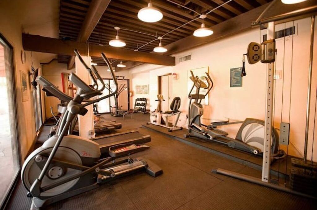 Un gimnasio con cintas de correr, elípticas y equipo de pesas.