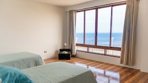 A room with two beds, a nightstand, a lamp, and a large window with curtains. - Hotel Sueños de Chicama (Rázuri)