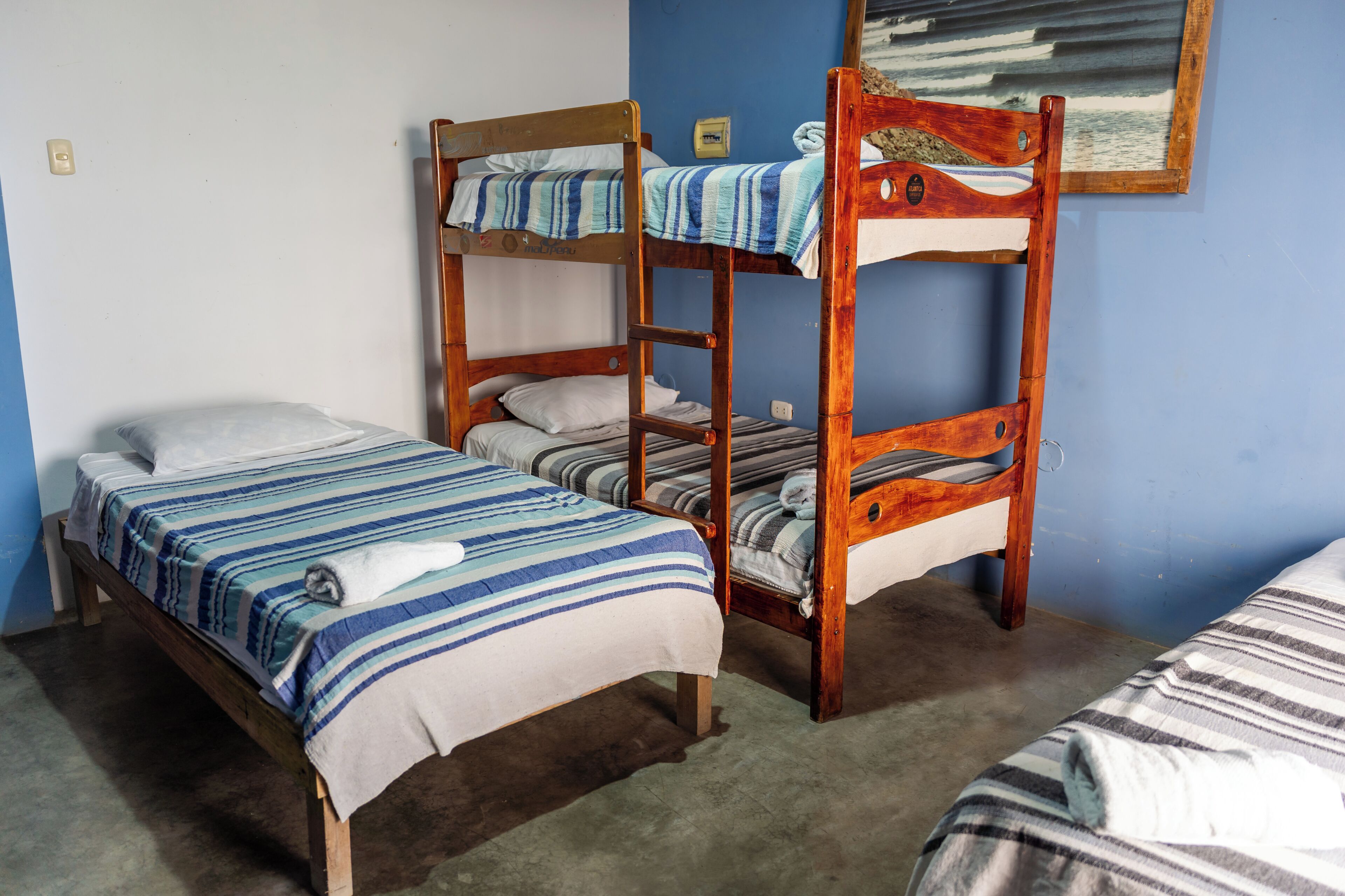 Una habitación con dos literas, una cama individual y un cuadro en la pared.