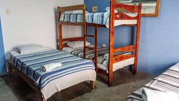 Una habitación con dos literas, una cama individual y un cuadro en la pared.