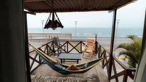 A hammock chair on a wooden deck overlooking the beach. - Hotel Sueños de Chicama (Rázuri)