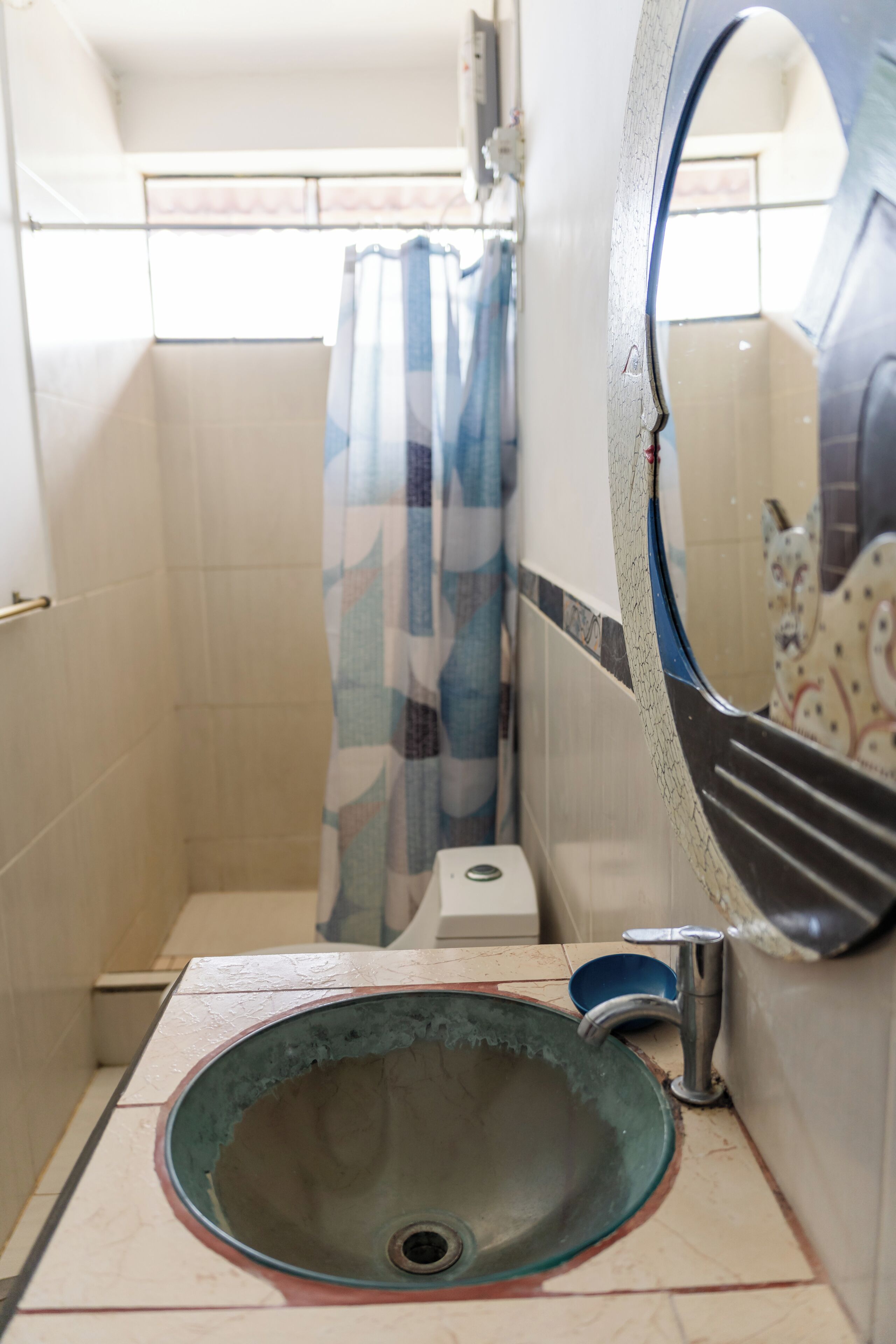 A bathroom with a sink, a mirror, a shower curtain, and a toilet.