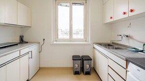 Une cuisine de taille réduite avec des meubles blancs, un évier à deux bacs et une fenêtre.
