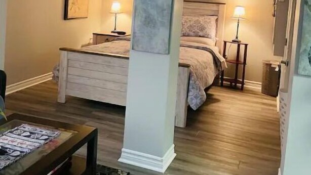 Une chambre à coucher avec un lit, des lampes de chevet, une table de nuit et un grand tableau abstrait accroché au mur.