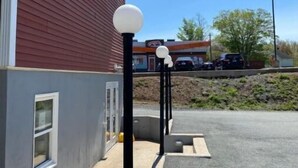 A parking area with a red building and a grey wall. - Abigael’s Apt Suite 1 BR 2 BED in Central Bridgewater

 (Bridgewater)