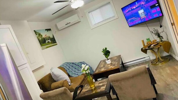 A compact living space with a sofa, a dining table, and a TV mounted on the wall. - Abigael’s Apt Suite 1 BR 2 BED in Central Bridgewater

 (Bridgewater)
