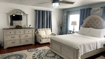 A bedroom with a bed, dresser, vanity, and a ceiling fan.