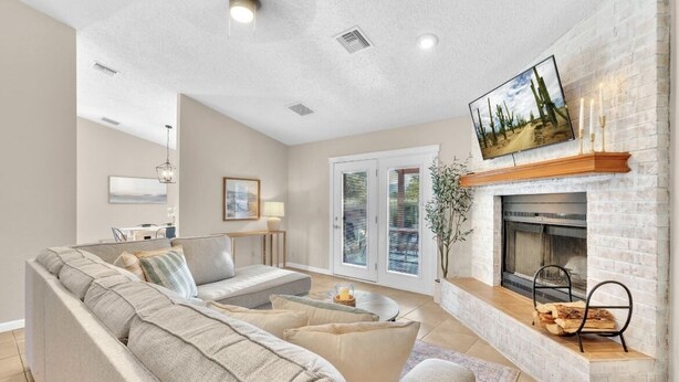 A living room with a sectional sofa, a fireplace, and a television mounted above it. - NEW Mountain View 4 BDRM Home with Pool & Spa, right on a Golf Course (Sierra Vista)