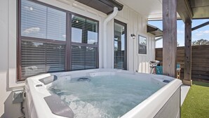 A hot tub in a backyard with a wooden deck and a house in the background. - *New Romantic Getaway|Hot Tub (Fredericksburg)
