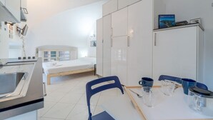 Una habitación moderna y bien iluminada con cocina, una cama y una mesa de comedor con sillas.