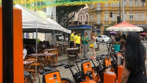 Outdoor seating with tables and chairs, a bike rental station, and a white tent.