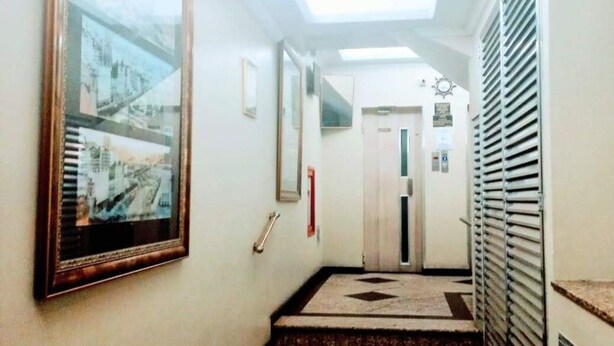 A hallway with a framed picture on the left, a handrail, and a door at the end.