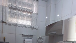 A small kitchen with white cabinets, a sink, a coffee maker, and a refrigerator.
