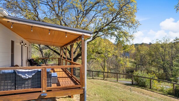 A wooden deck with a covered seating area and a staircase leading to a second level.